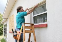 man in blue shirt putting screen on window