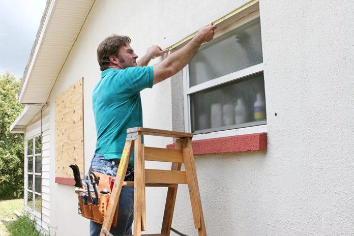 man in blue shirt putting screen on window