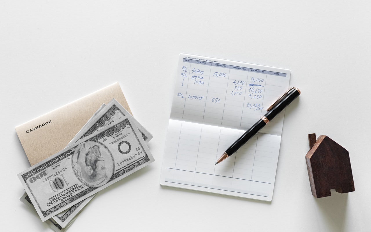 pen on top of white paper, cashbook and a hundred US dollar bill to illustrate the best home insurance companies