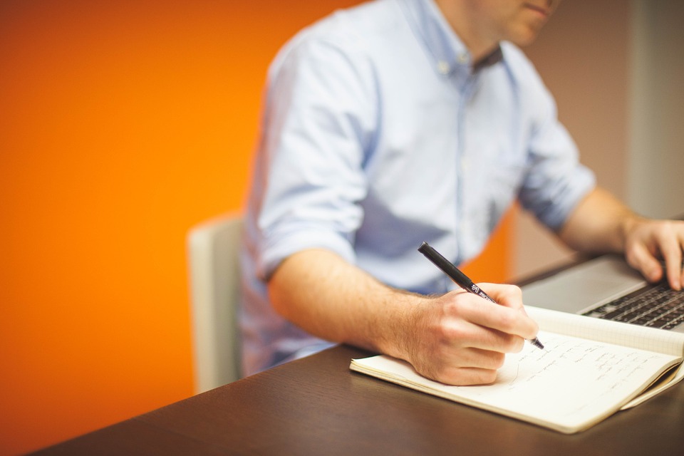 Man writing while looking at the laptop
